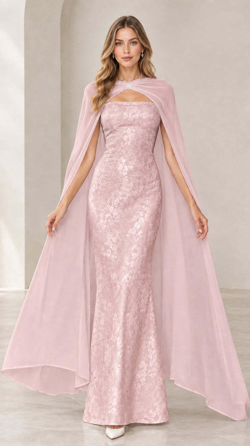 Model wearing blush pink strapless lace mermaid gown with matching blush sheer cape