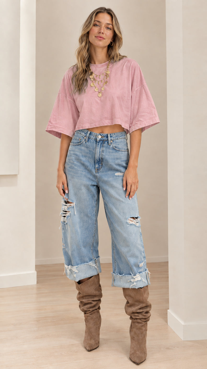 Model wearing dusty pink cropped tee paired with distressed cuffed denim jeans
