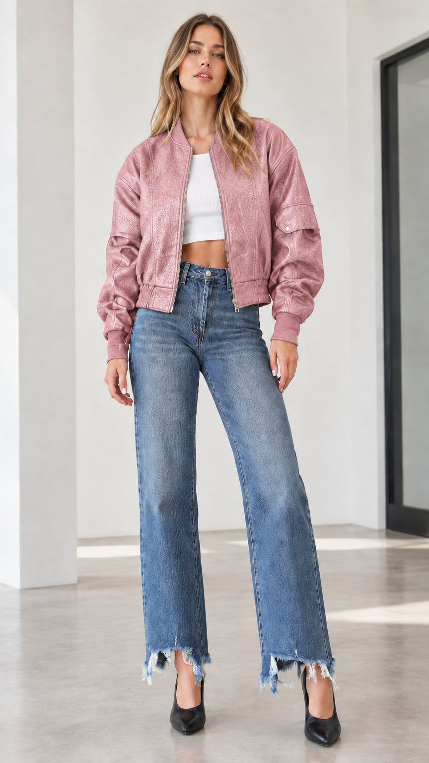 Model wearing a dusty pink textured faux leather bomber jacket with wide-leg denim