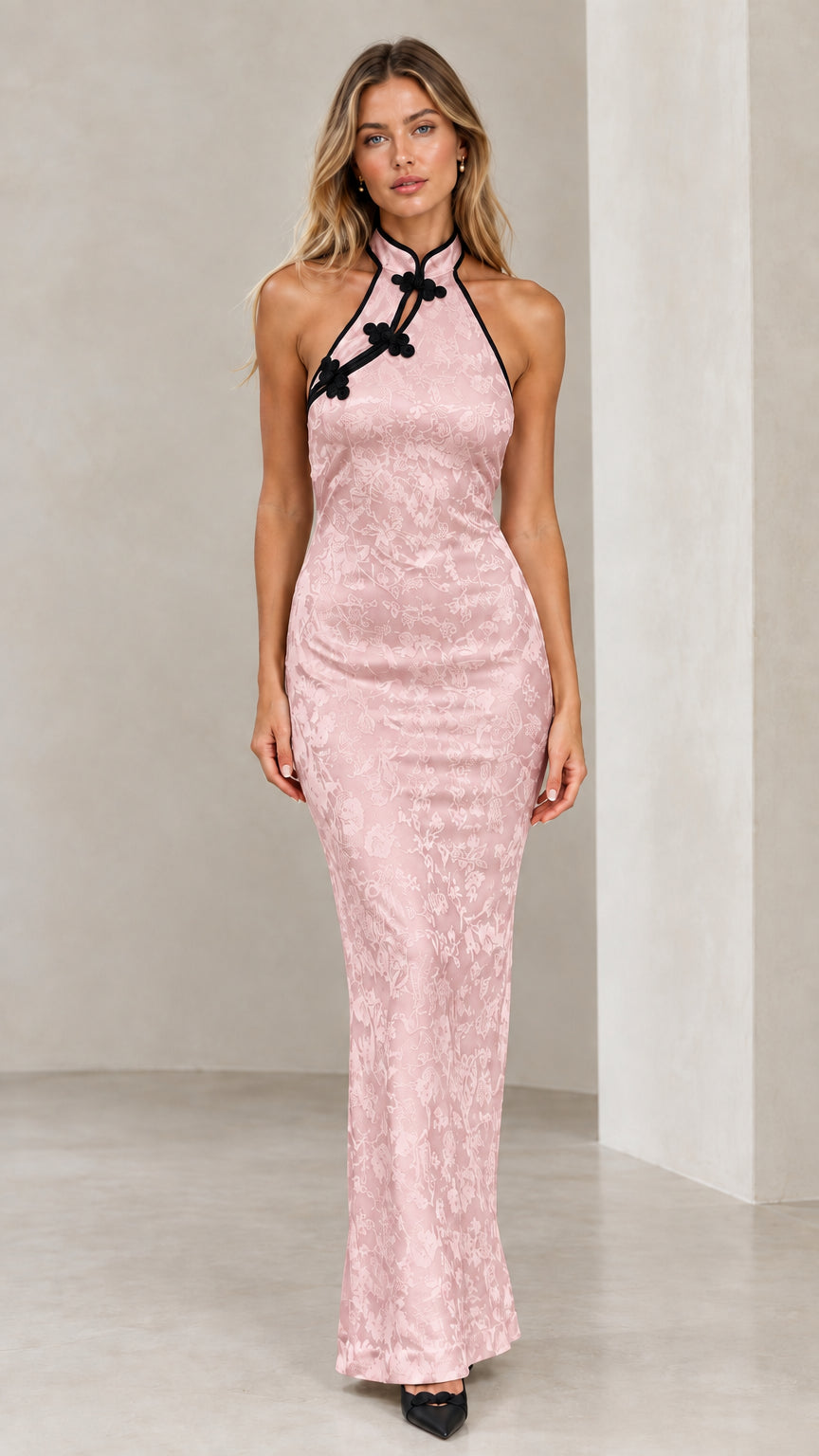 Model wearing blush pink jacquard halter maxi dress with black piped trim