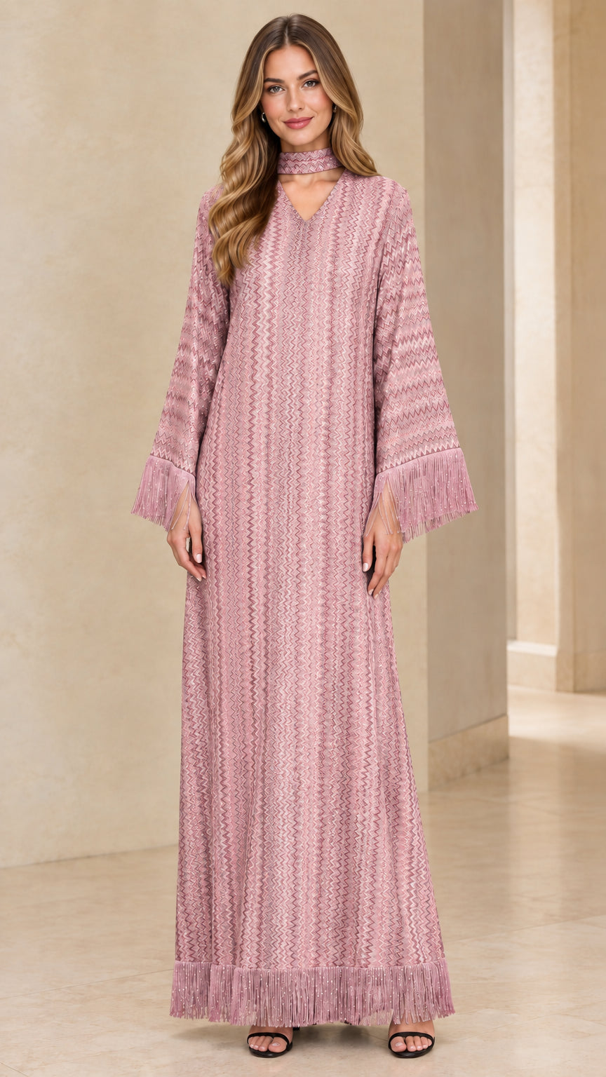 Front view of woman wearing dusty pink long sleeve maxi dress with chevron texture and fringe trim