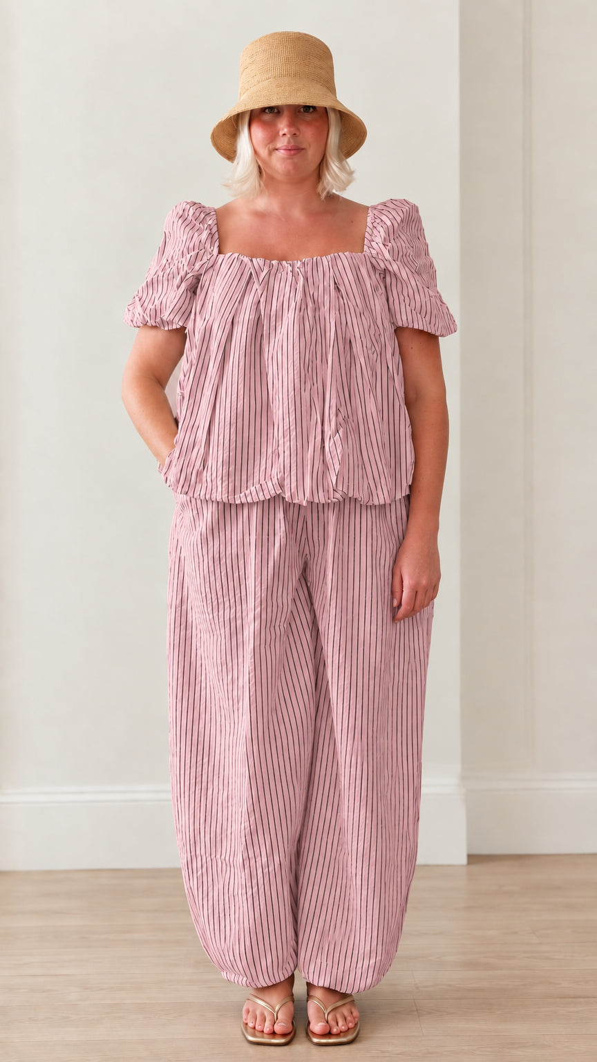 Woman wearing pink striped square neck puff sleeve top and matching lantern pants set