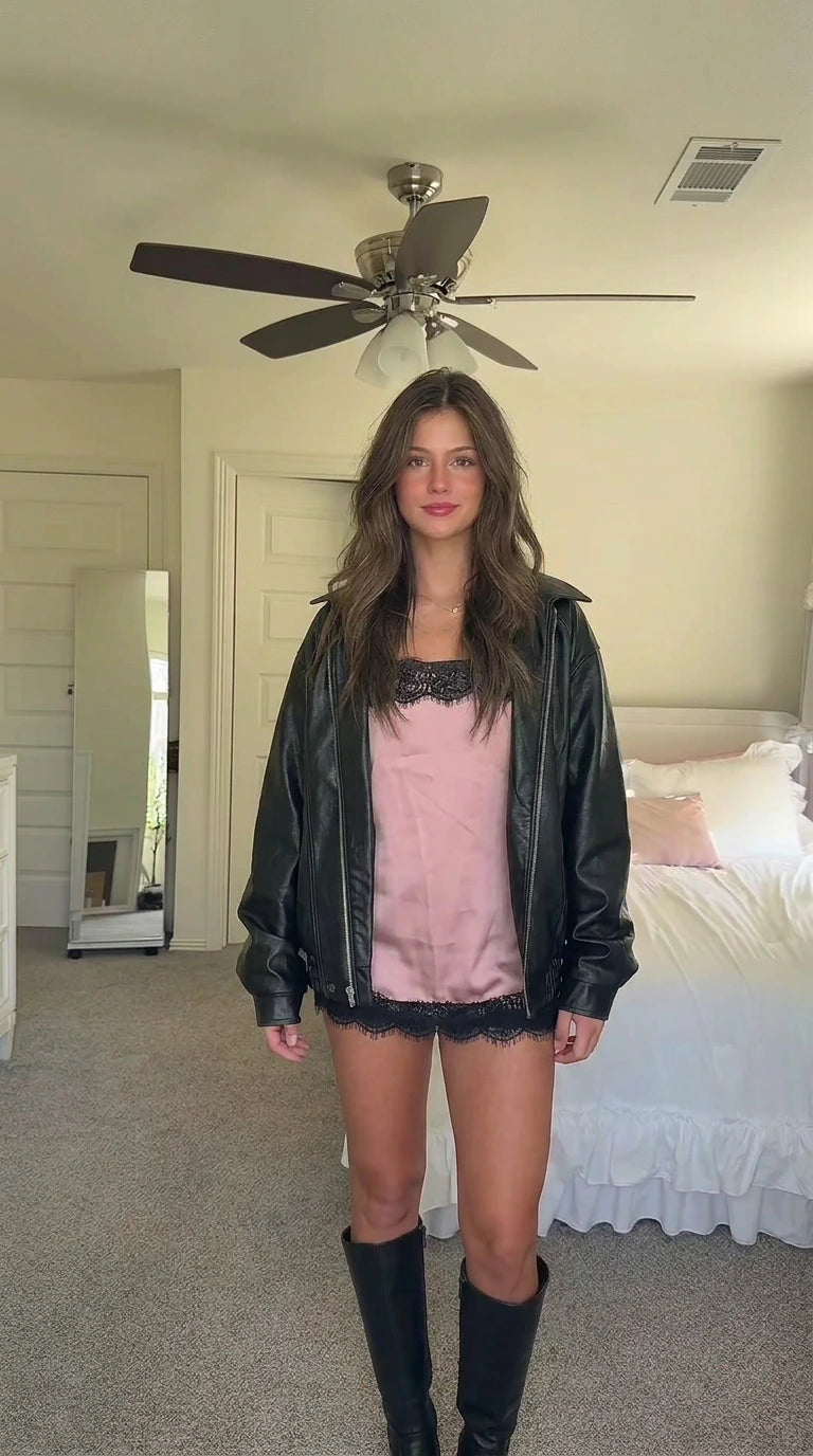 Black faux leather bomber jacket layered over pink lace cami set