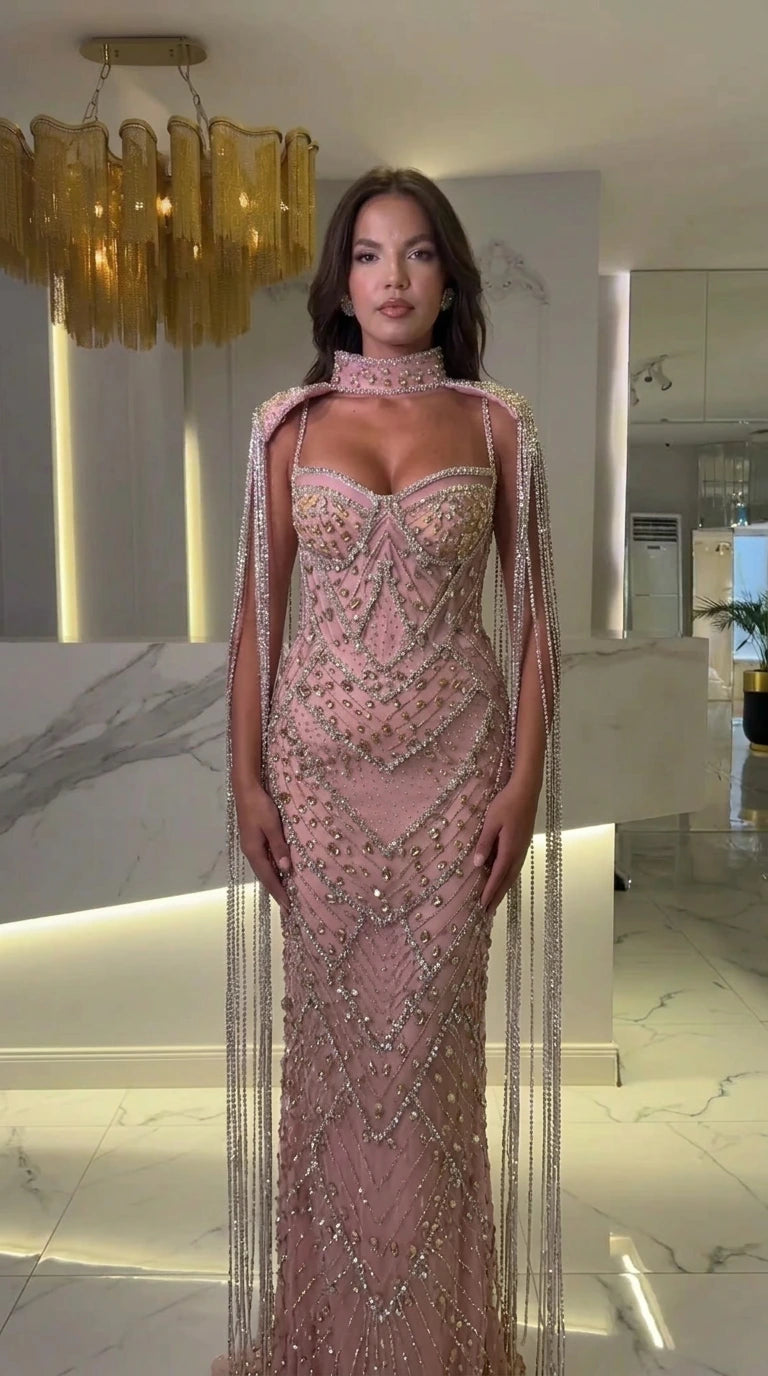 Front view of blush pink rhinestone embellished formal evening gown with fringe capelet