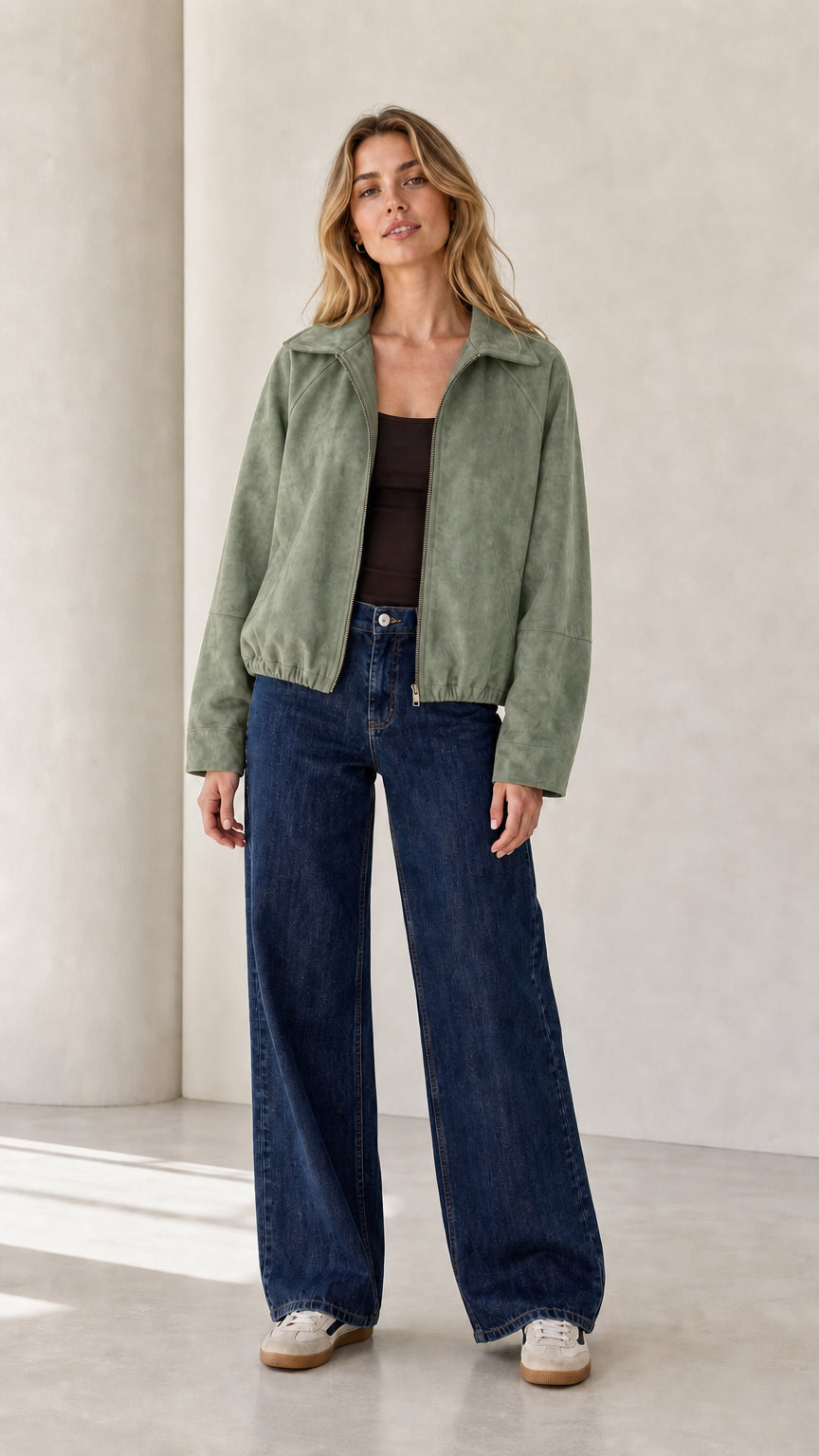 Front view of the sage green cropped faux suede jacket styled with denim