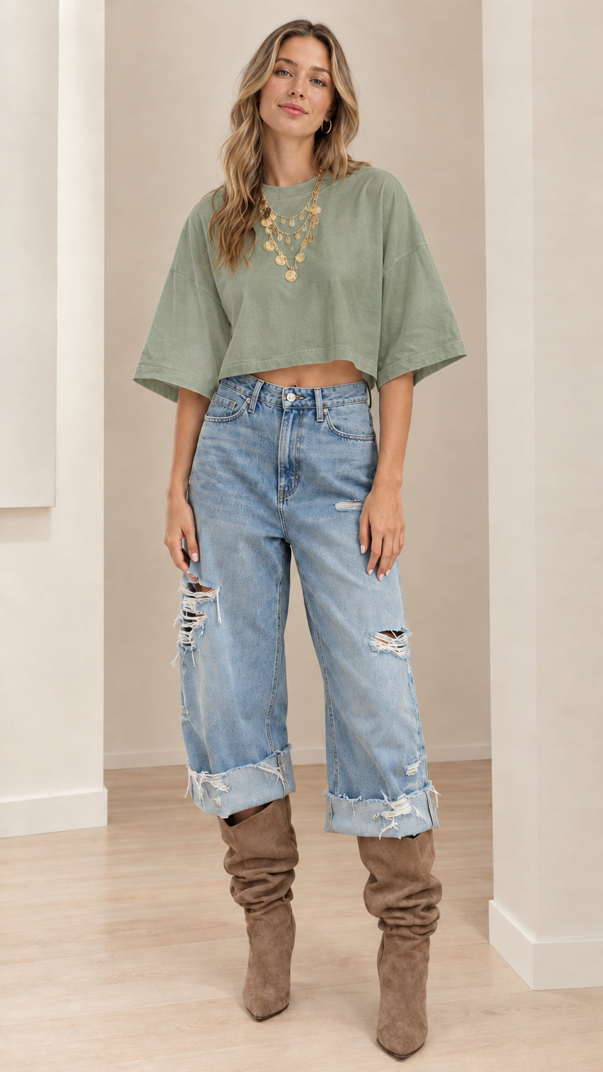 Model wearing sage green cropped t-shirt paired with distressed cuffed denim jeans