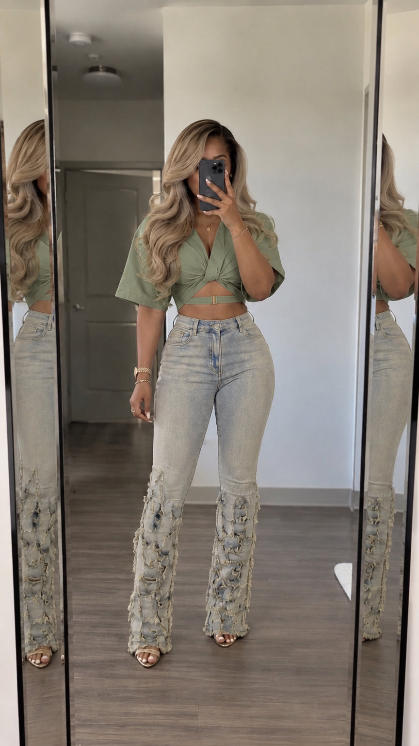 Front view of woman wearing sage green wrap crop top and light-wash fringed flare jeans