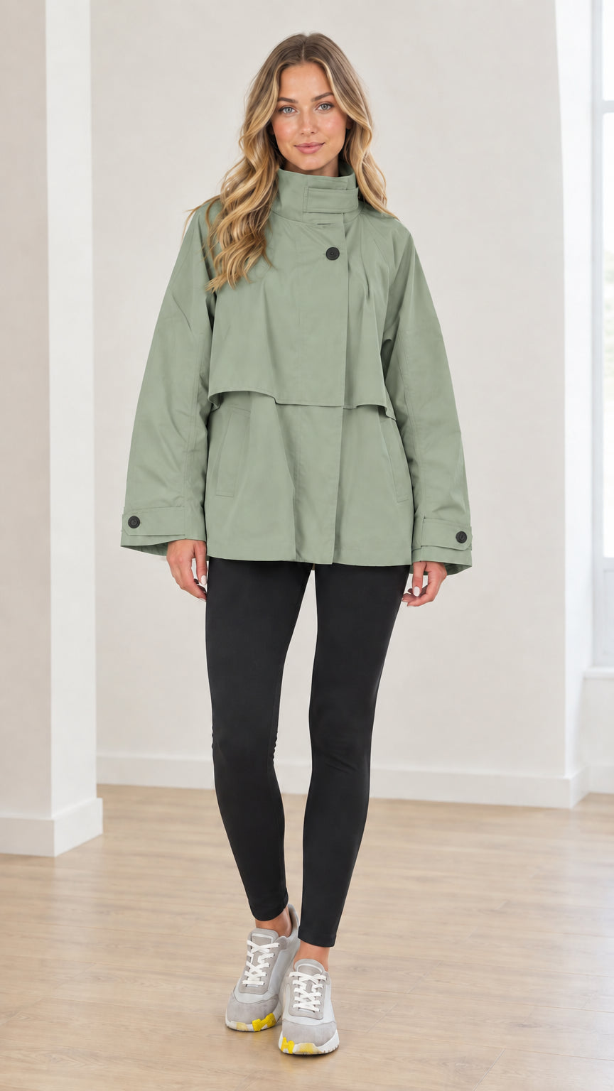 Front view of woman wearing sage green high neck layered short trench coat