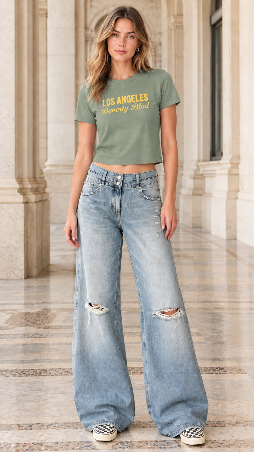 Model wearing sage green graphic baby tee paired with light-wash ripped wide-leg jeans