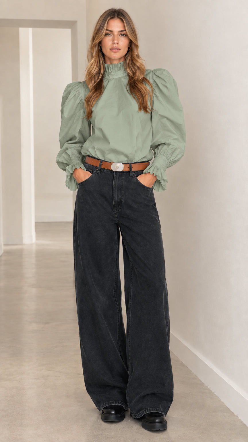 Woman wearing sage green high-neck puff-sleeve top paired with wide-leg dark wash pants