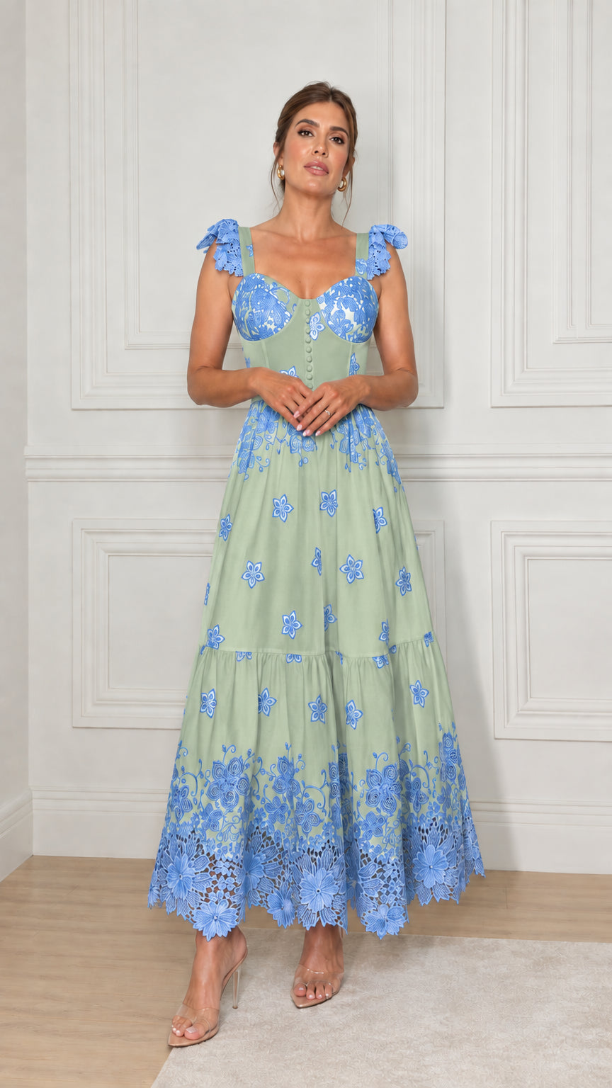Model wearing sage green tiered maxi dress featuring blue floral embroidery and lace hem