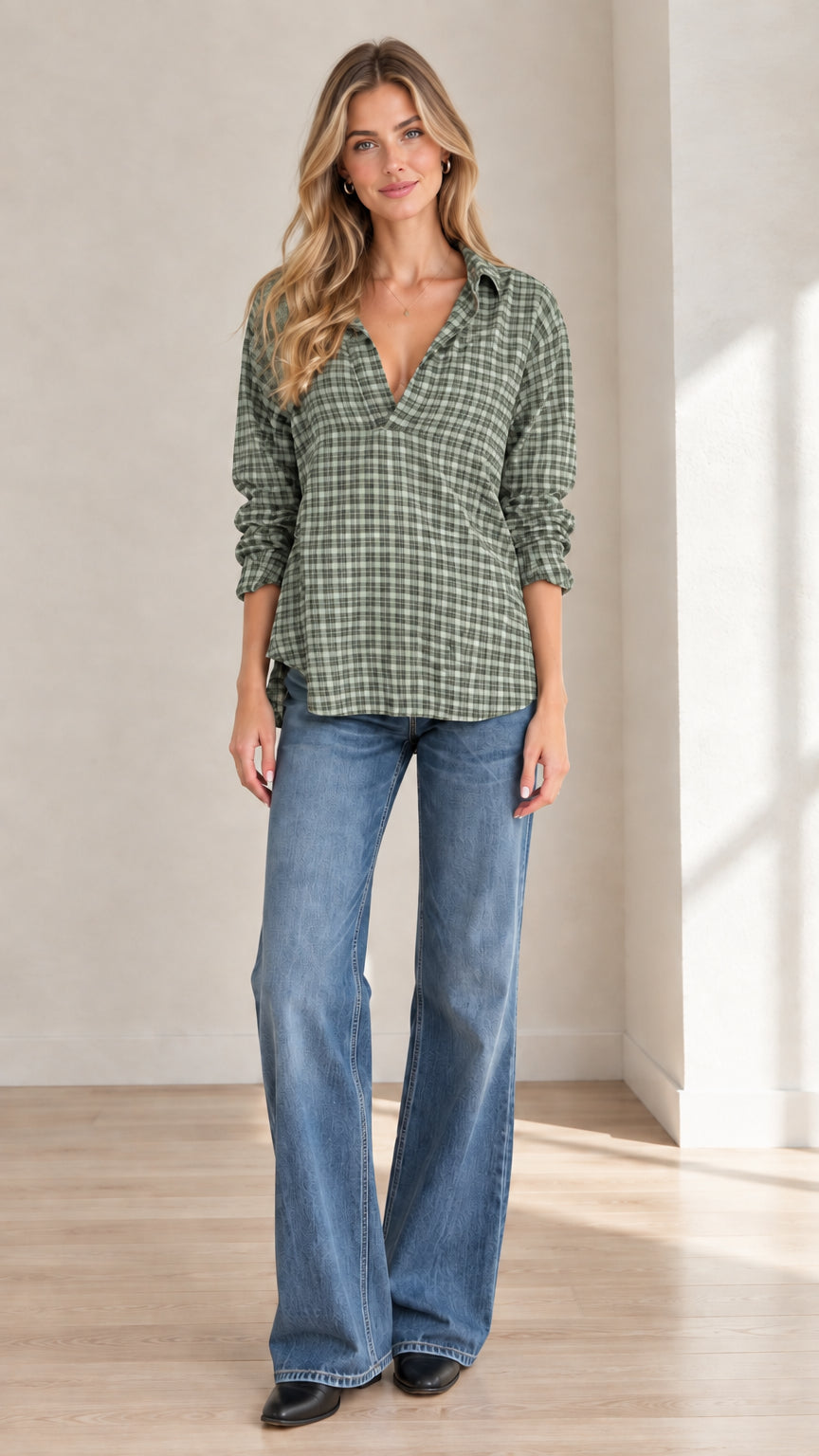 Full front view of model wearing sage green plaid popover blouse with flare jeans