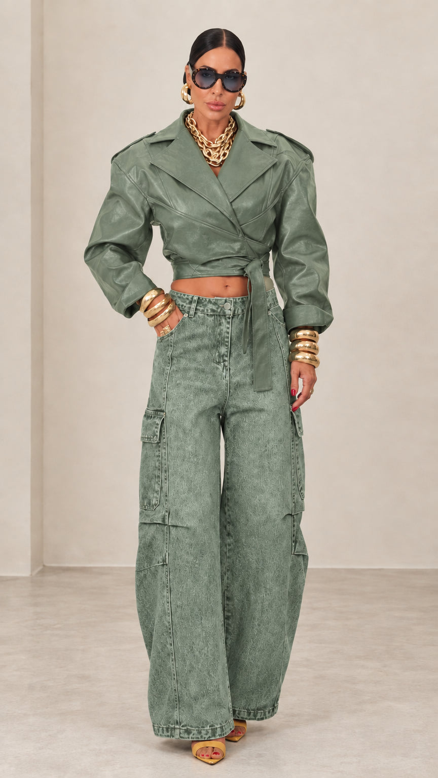 Model wearing sage green cropped faux leather wrap jacket with matching cargo trousers