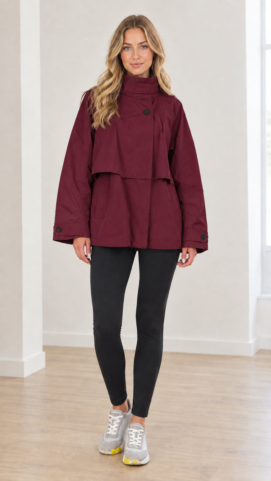 Front view of woman wearing burgundy wine red high neck layered short trench coat