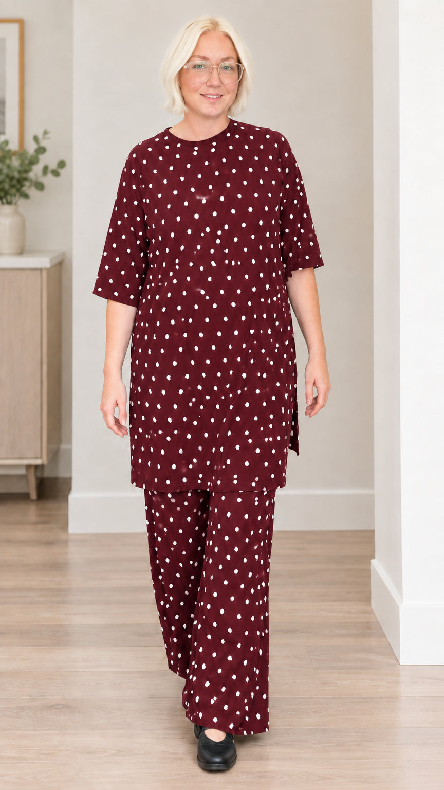 Front view of woman wearing burgundy polka dot matching tunic and trousers set