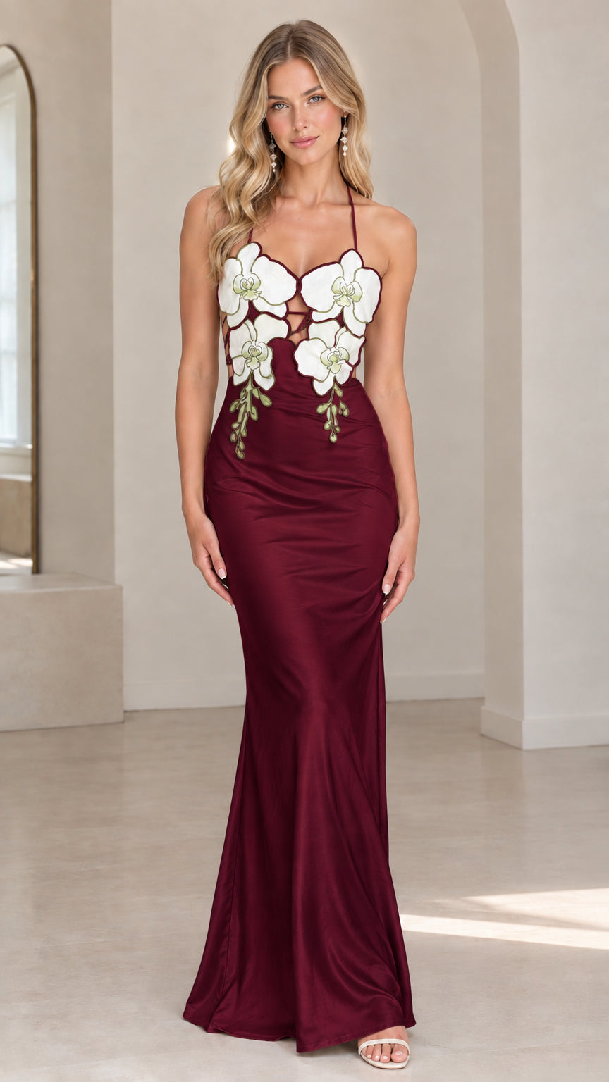 Front view of model wearing burgundy wine satin halter maxi dress with floral appliqués
