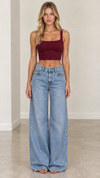 Full-body front view of woman wearing light blue wide-leg jeans styled with burgundy crop top