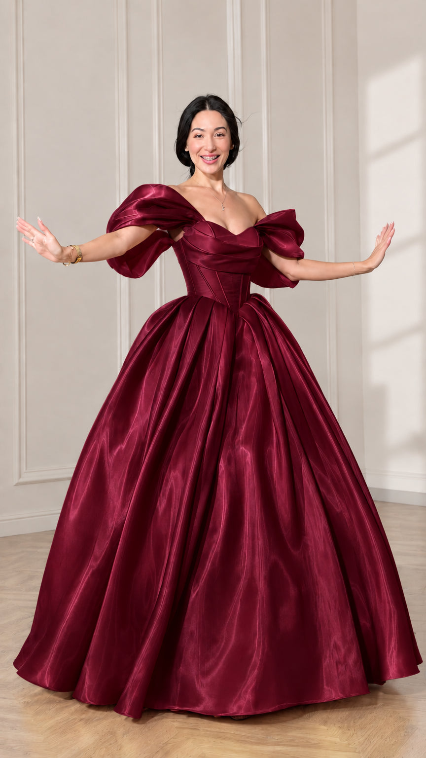 Front view of model wearing a deep burgundy off-shoulder puff sleeve corset ball gown