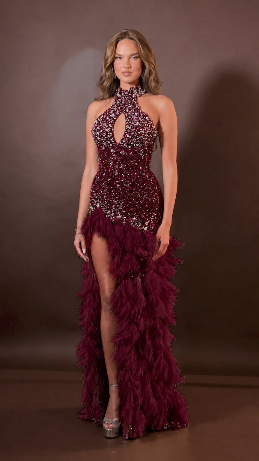 Front view of model wearing burgundy wine rhinestone halter evening gown with burgundy feather trim