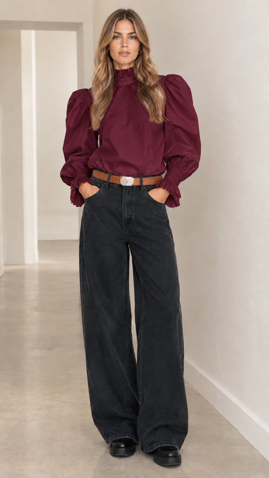 Woman wearing burgundy wine ruffle high-neck puff-sleeve blouse and dark wide-leg trousers