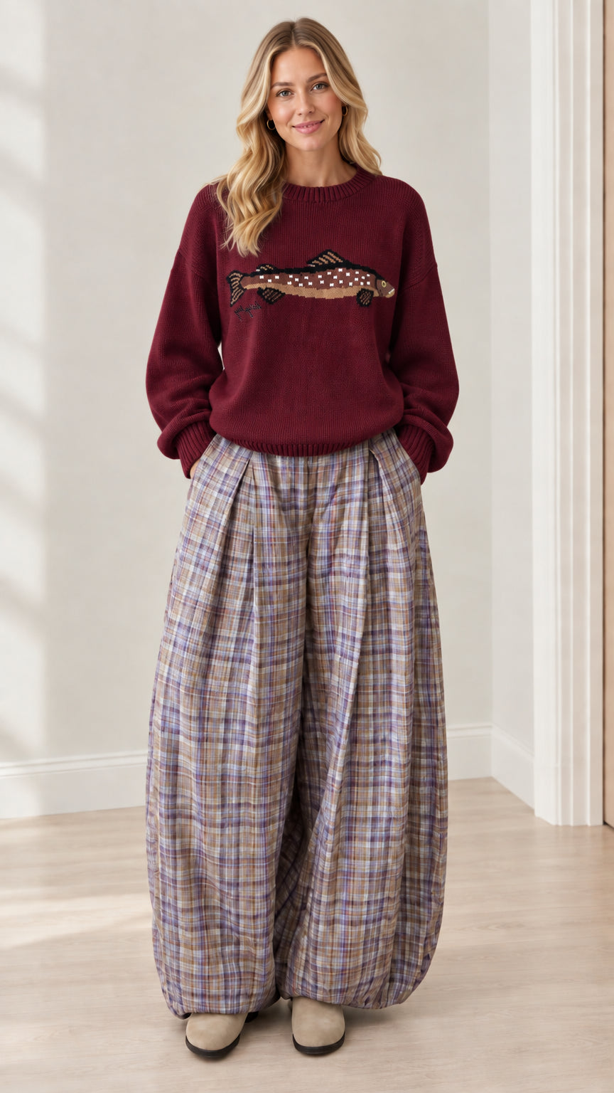 Model wearing rich burgundy graphic crewneck sweater and balloon plaid pants