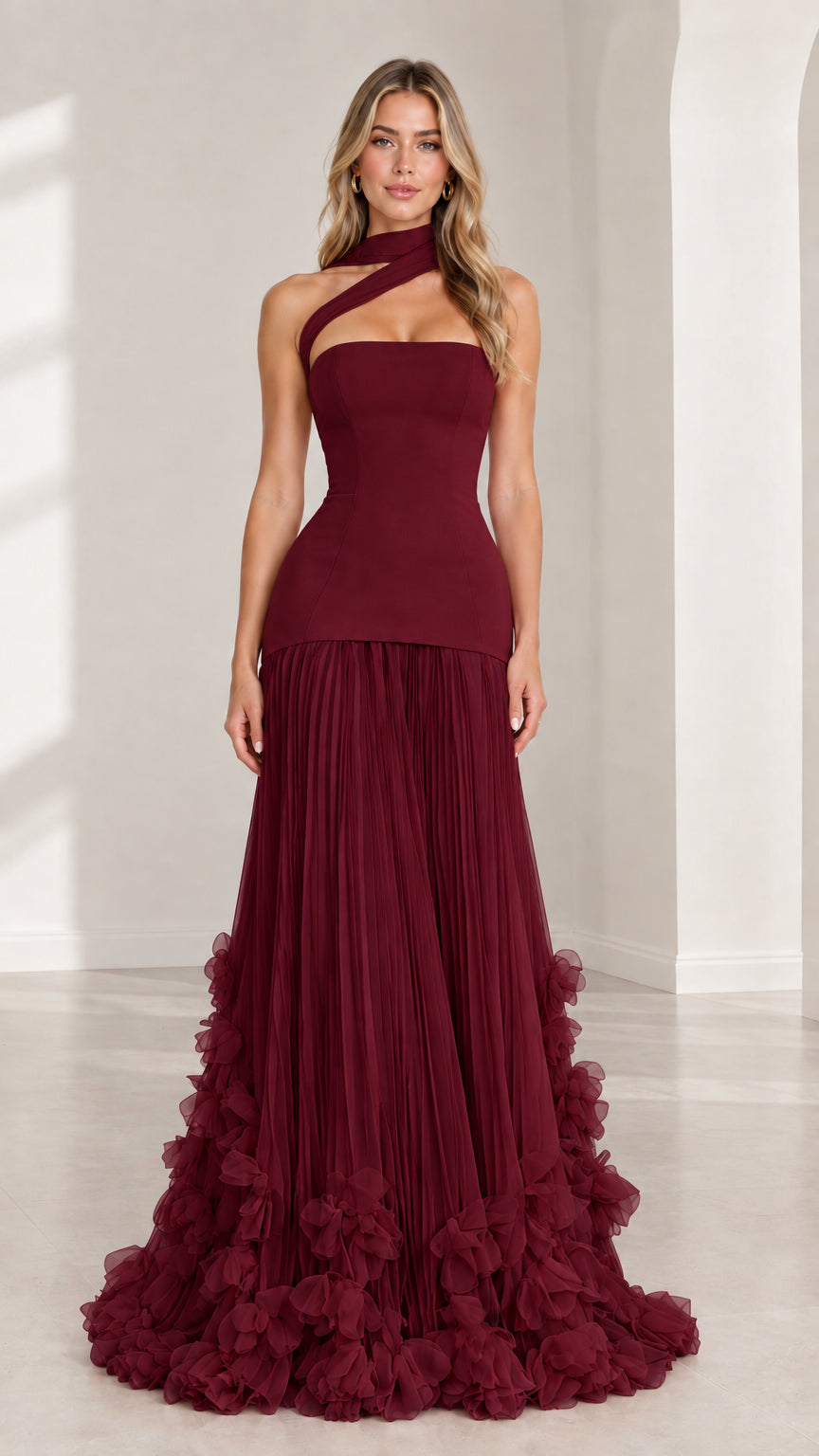 Front full-length view of model wearing burgundy red asymmetric drop waist evening gown