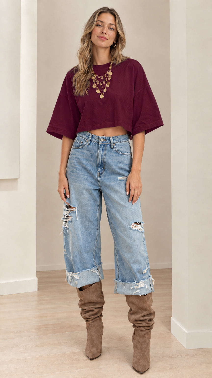 Model wearing burgundy cropped t-shirt styled with light-wash cuffed denim jeans