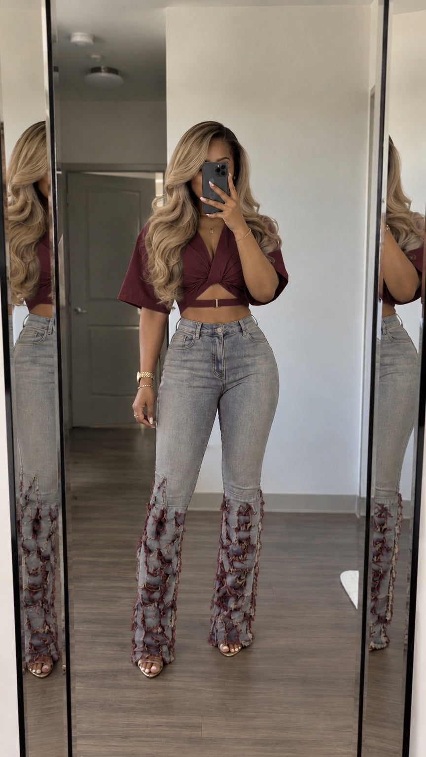 Front view of woman wearing burgundy wrap crop top and matching fringed flare jeans