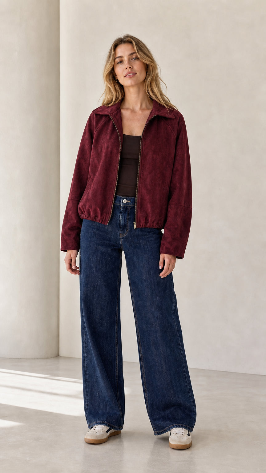 Front view of the burgundy cropped faux suede jacket styled with denim
