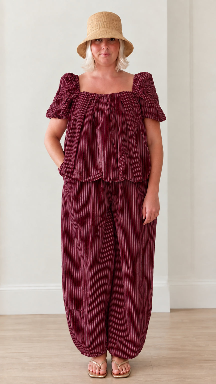 Woman wearing burgundy striped square neck puff sleeve top and matching lantern pants set