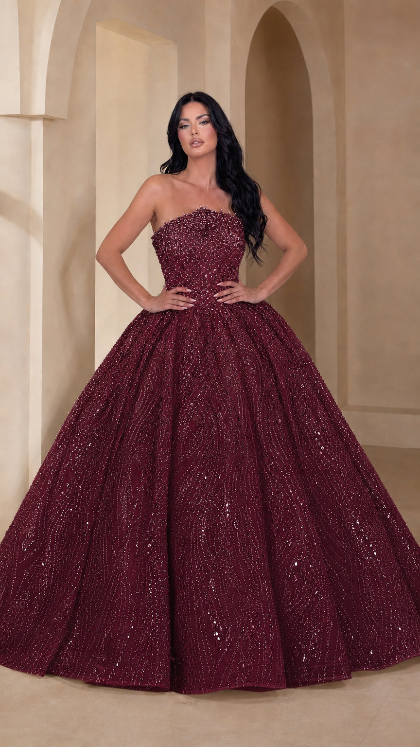 Model wearing deep burgundy wine strapless beaded ball gown