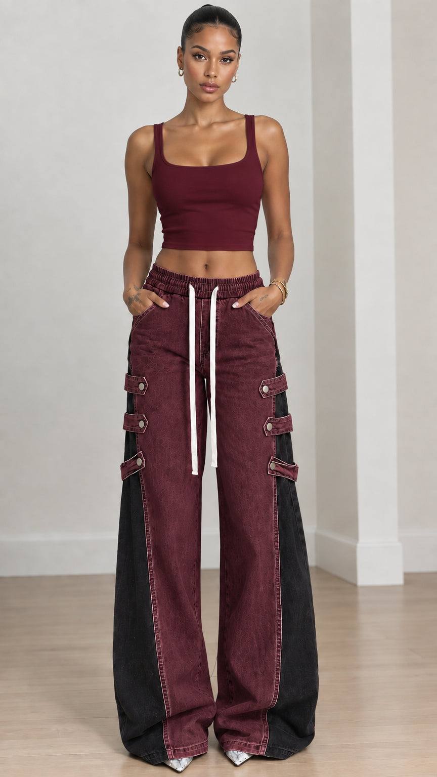 Full front view of burgundy red and black colorblock wide-leg jeans with strap accents