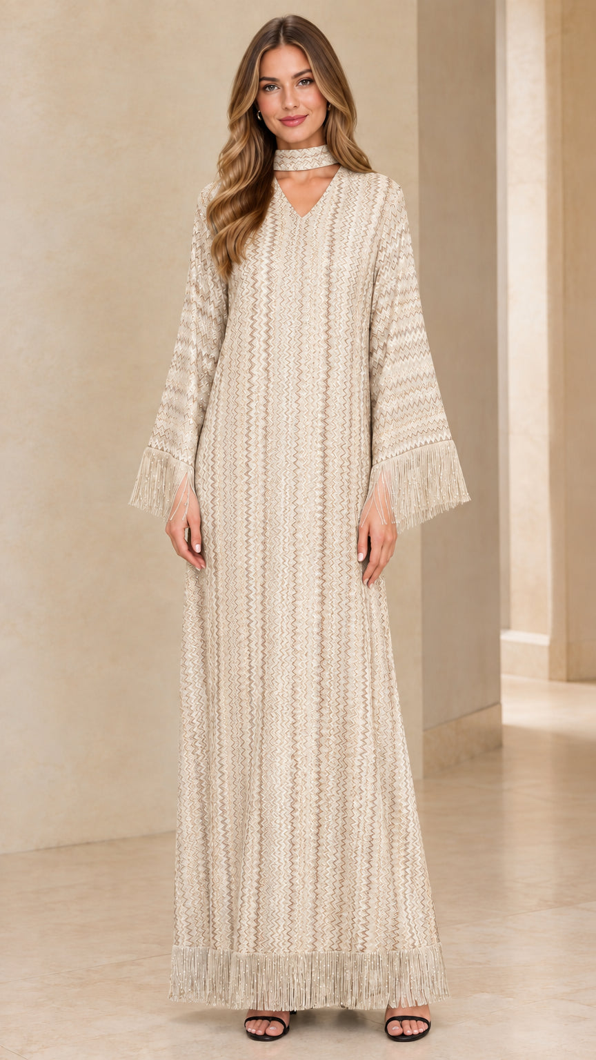 Front view of woman wearing beige cream chevron knit long sleeve maxi dress with fringe cuffs and hem
