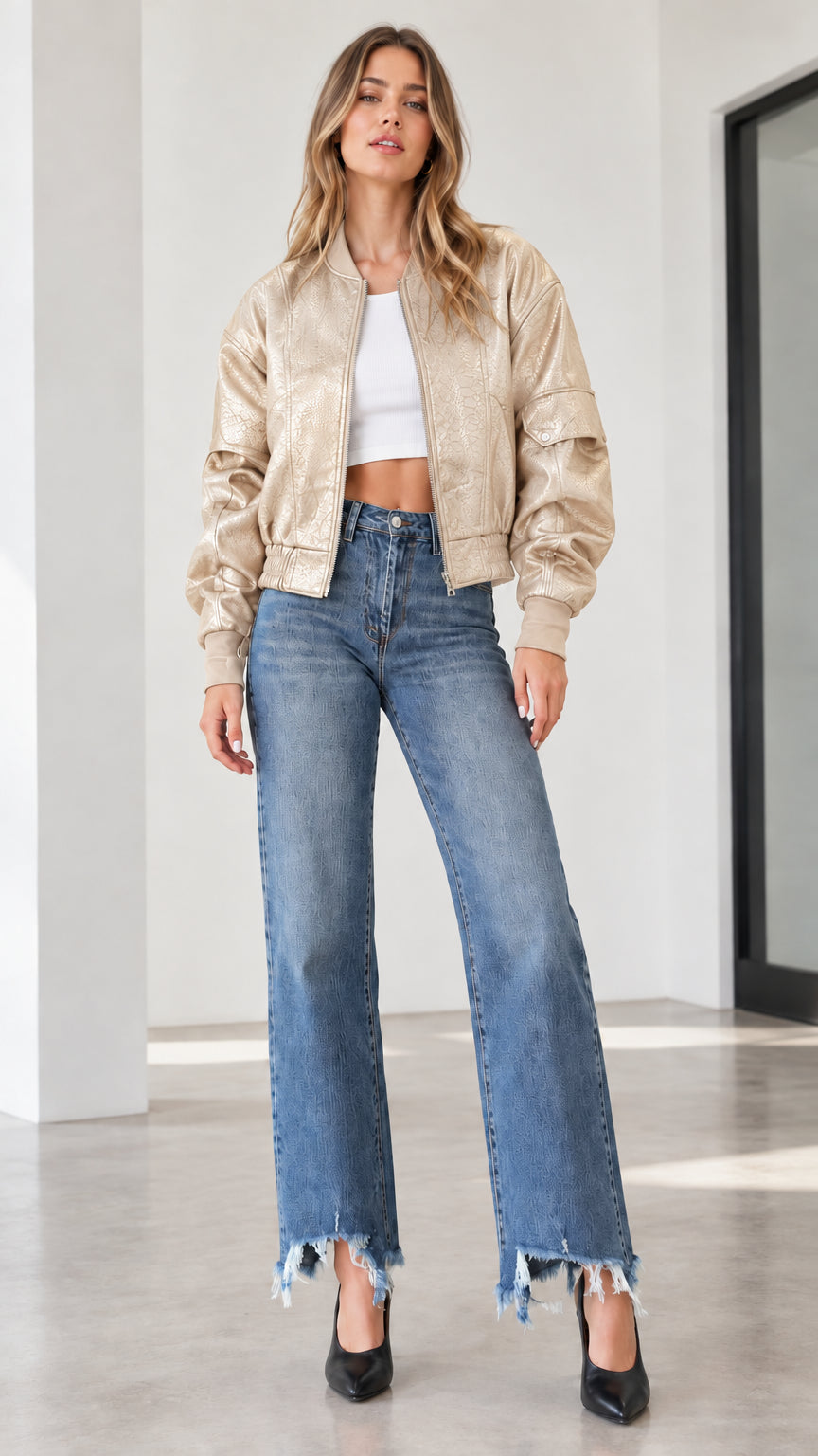 Model wearing a champagne beige textured faux leather bomber jacket with wide-leg denim