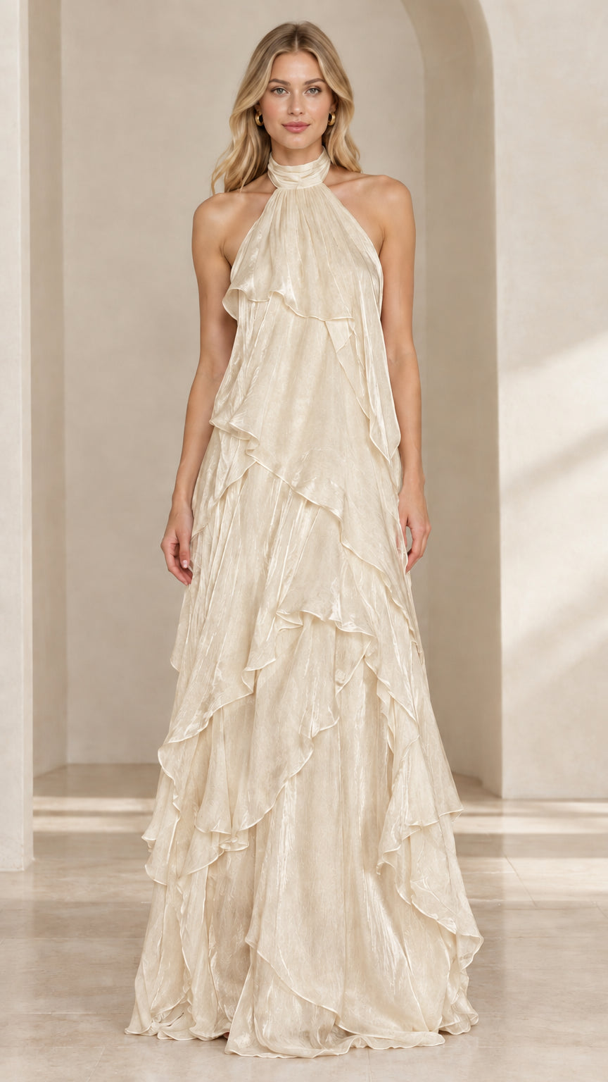 Front view of woman wearing a champagne beige tiered ruffle halter maxi gown