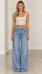 Full-body front view of woman wearing light blue wide-leg jeans styled with cream beige crop top