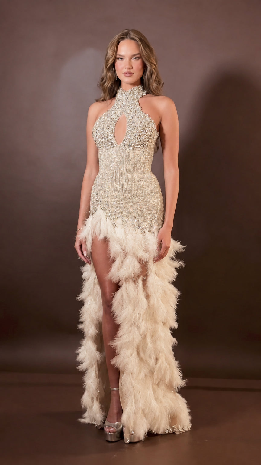 Front view of model wearing champagne gold rhinestone halter evening gown with beige feather trim