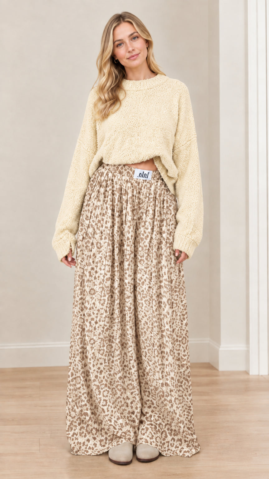 Model wearing cream beige knit sweater and matching beige leopard print flowing trousers