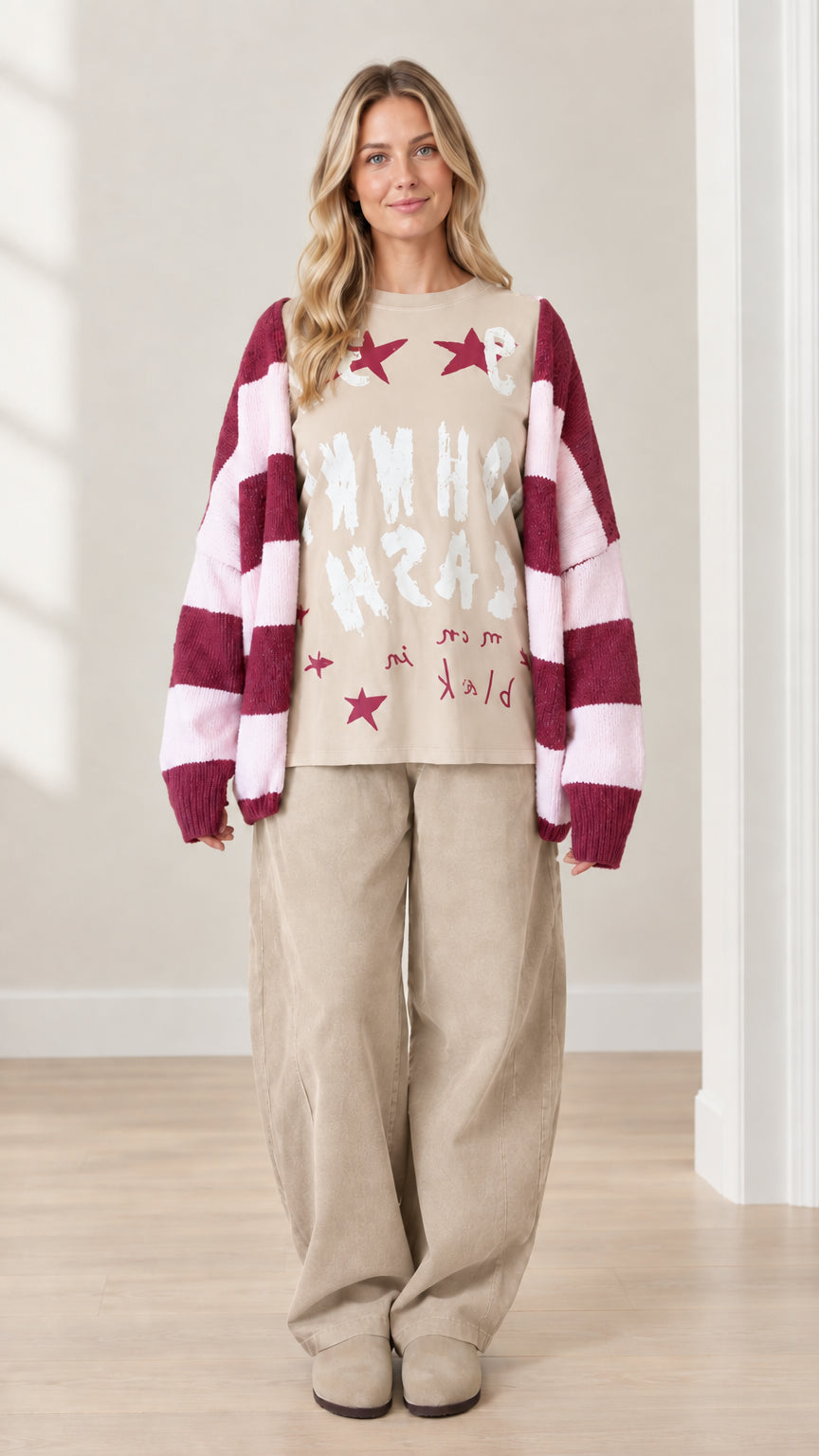 Full front view of model wearing beige graphic top with beige wide-leg pants and striped cardigan