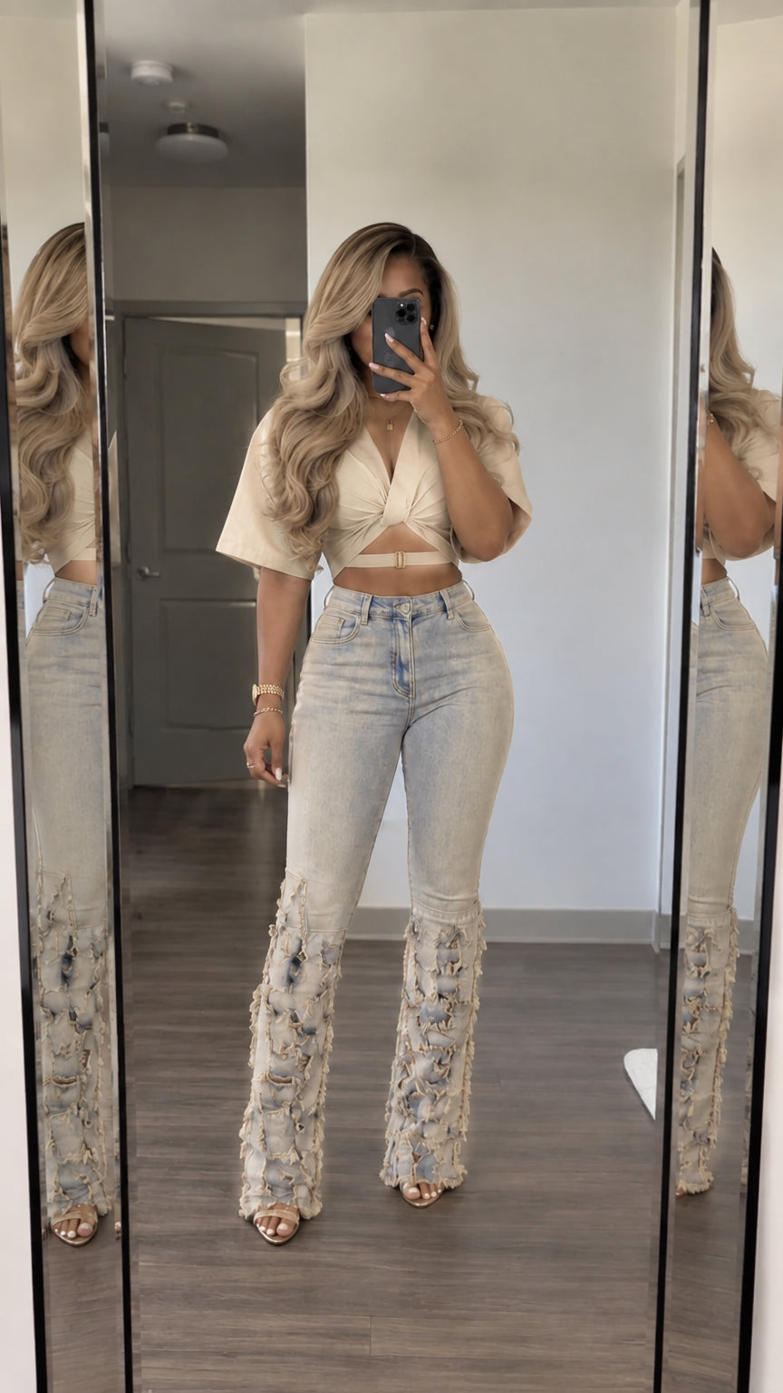 Front view of woman wearing cream wrap crop top and light-wash fringed flare jeans