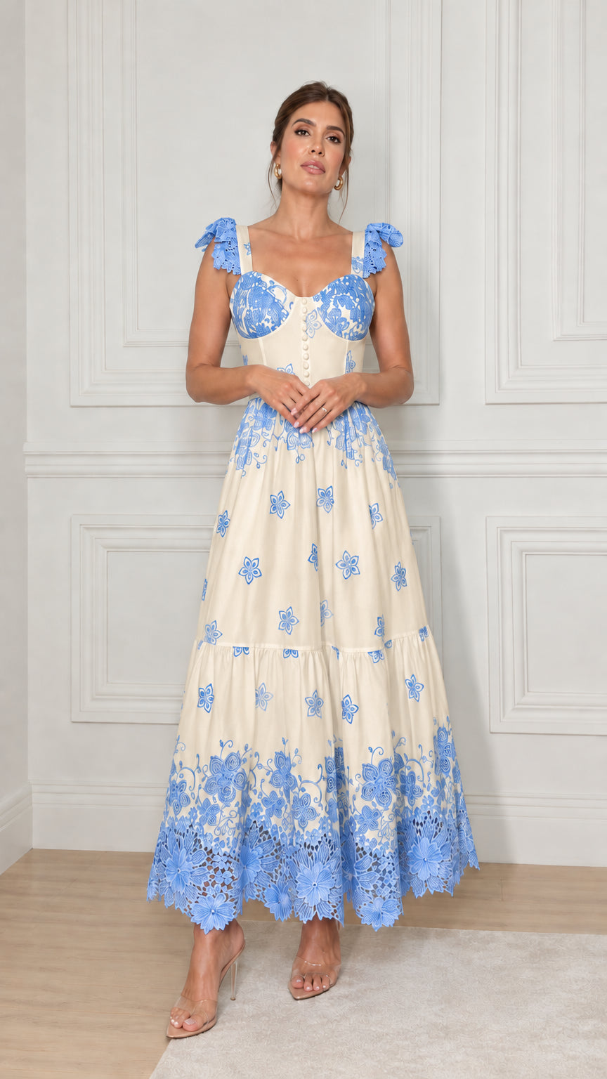 Model wearing cream tiered maxi dress with blue floral embroidery and lace trim