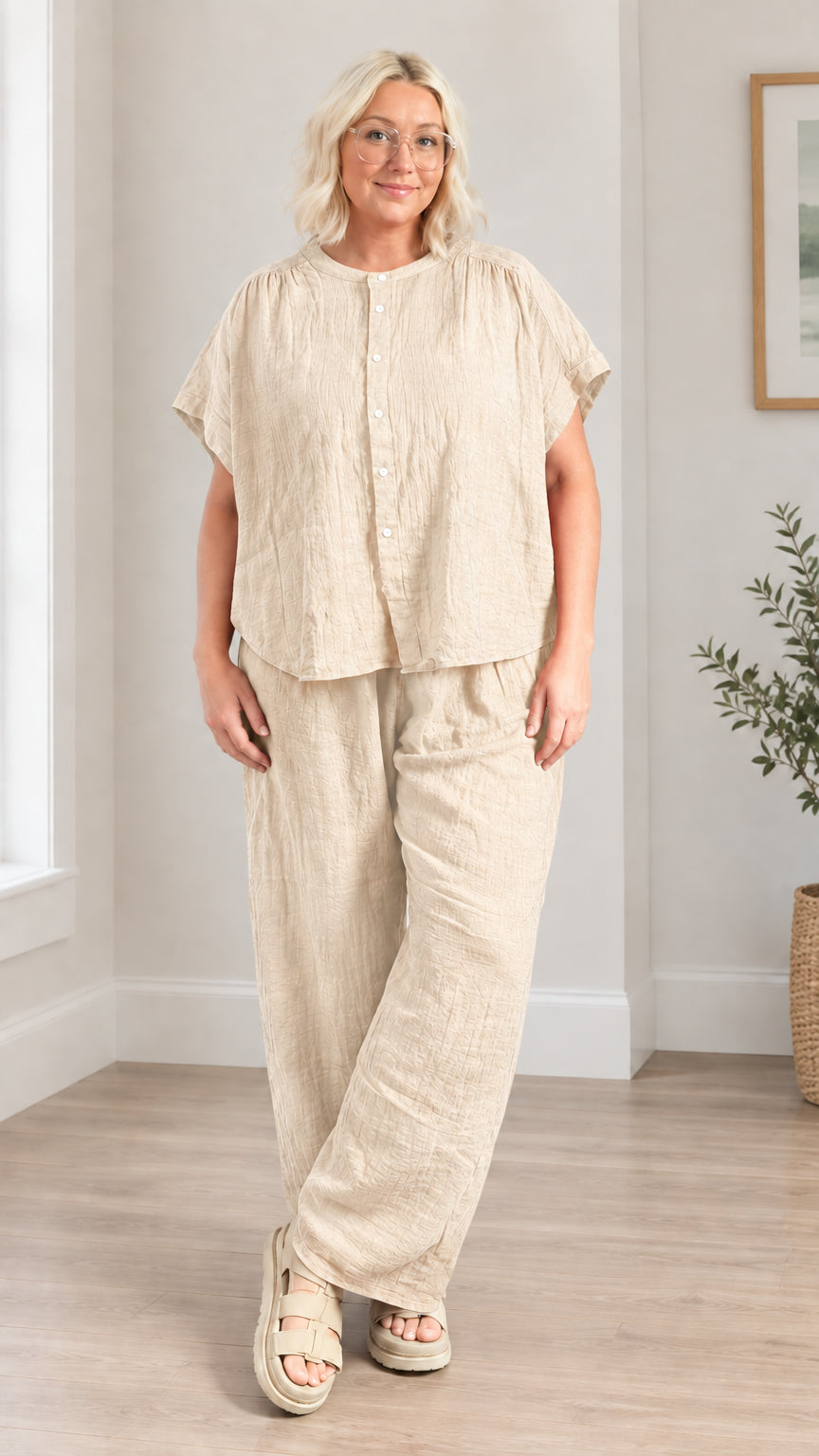 Model wearing beige neutral tone short-sleeve top and loose wide leg trousers set
