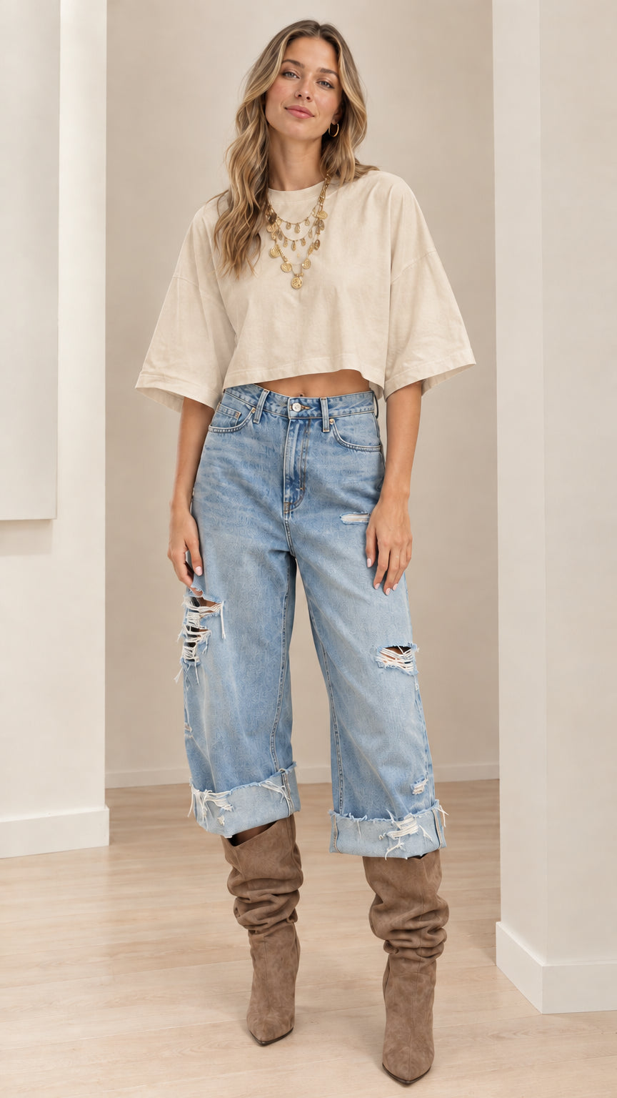 Model wearing beige cream cropped t-shirt styled with distressed cuffed denim jeans